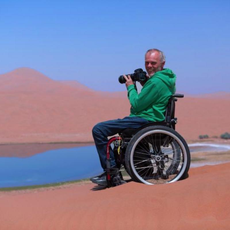 Anreas Pröve im Rollstuhl mit Foto in der Wüste