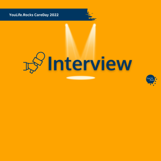 Schriftzug "Interview" in blauer Farbe, der Hintergrund ist orange. Der Schriftzug hat einen Schlagschatten und wird von oben von einem Spot angestrahlt. Links ist eine gezeichnete hand die ein Mikrofon hinstreckt.