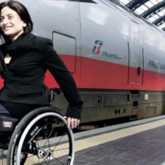 Rollstuhlfahrerin neben einem Zug auf dem Bahnsteig