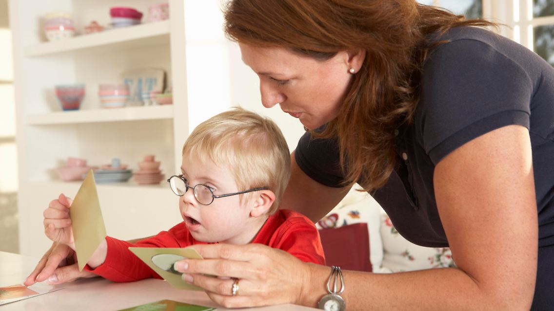 Mutter erklärt Ihrem Kind mit Down-Syndrom Karten mit Bildern