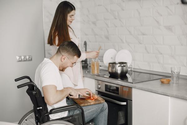 Bild zeigt Paar er im Rollstuhl beim Kochen 