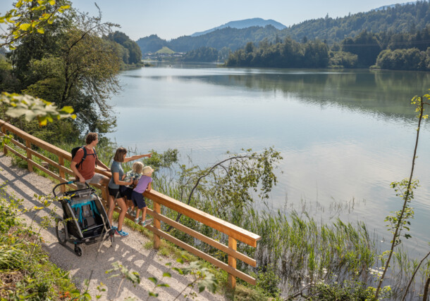 Bild zeigt Familie mit einem Geländekinderwagen die auf einen See schauen 