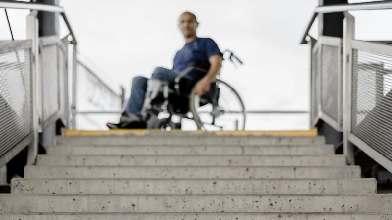 Mann im Rollstuhl vor Treppe 