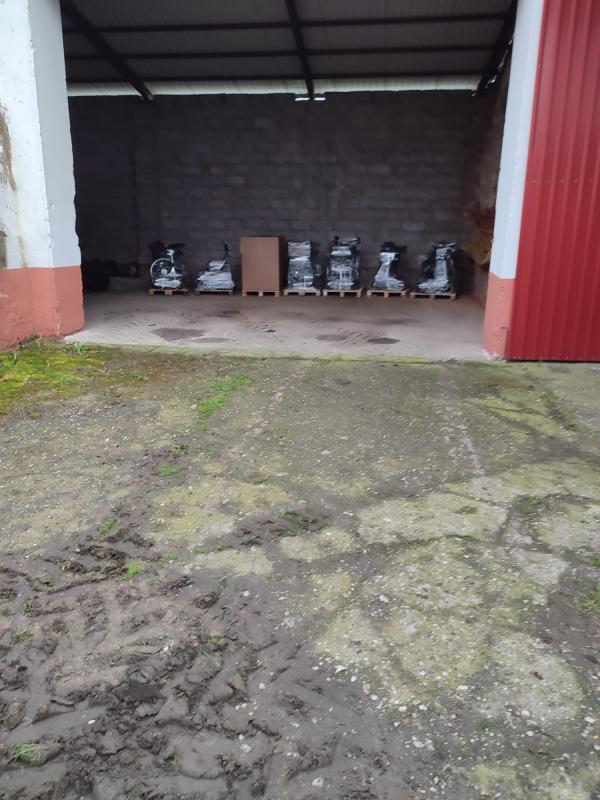 Blick durch ein offenes Tor einer Lagerhalle. Zu sehen sind 7 Europaletten mit Hilfsmitteln nebeneinander aufgereiht und warten auf den Abtransport.