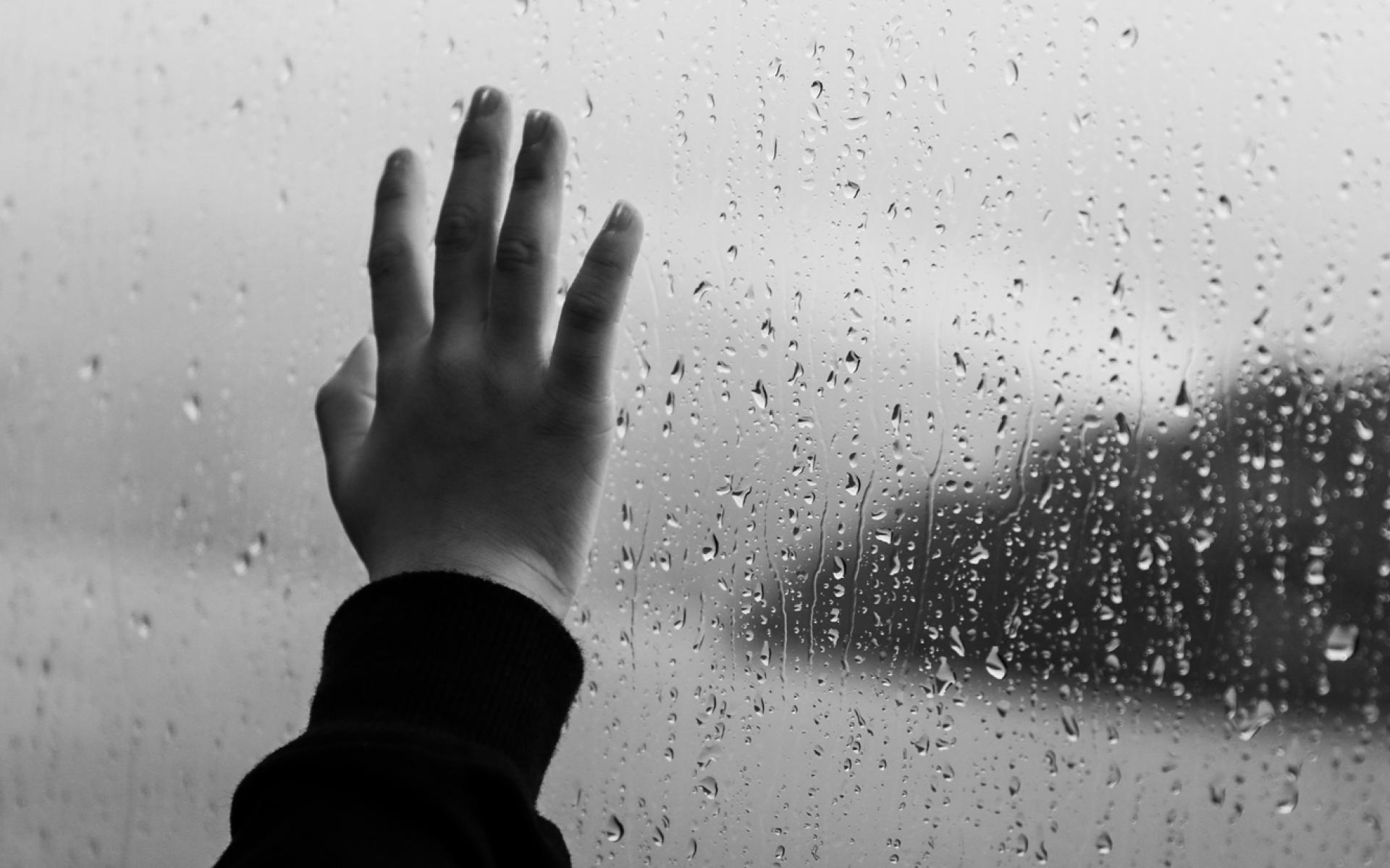 Hand am Regenassen Fenster