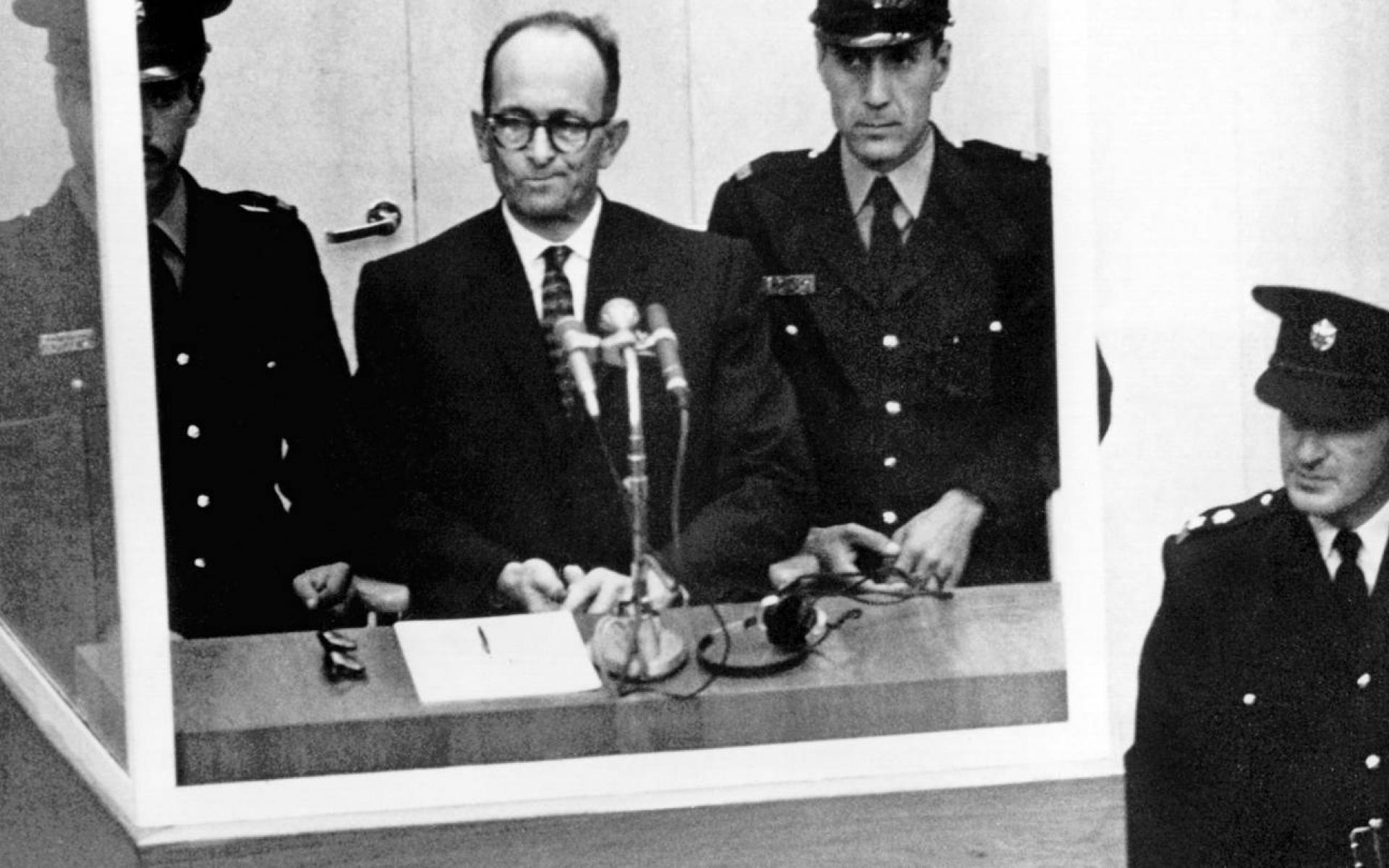 Bild zeigt Bild aus dem Gerichtsaal Eichmann mitte umringt von Justizbeamten in Uniform