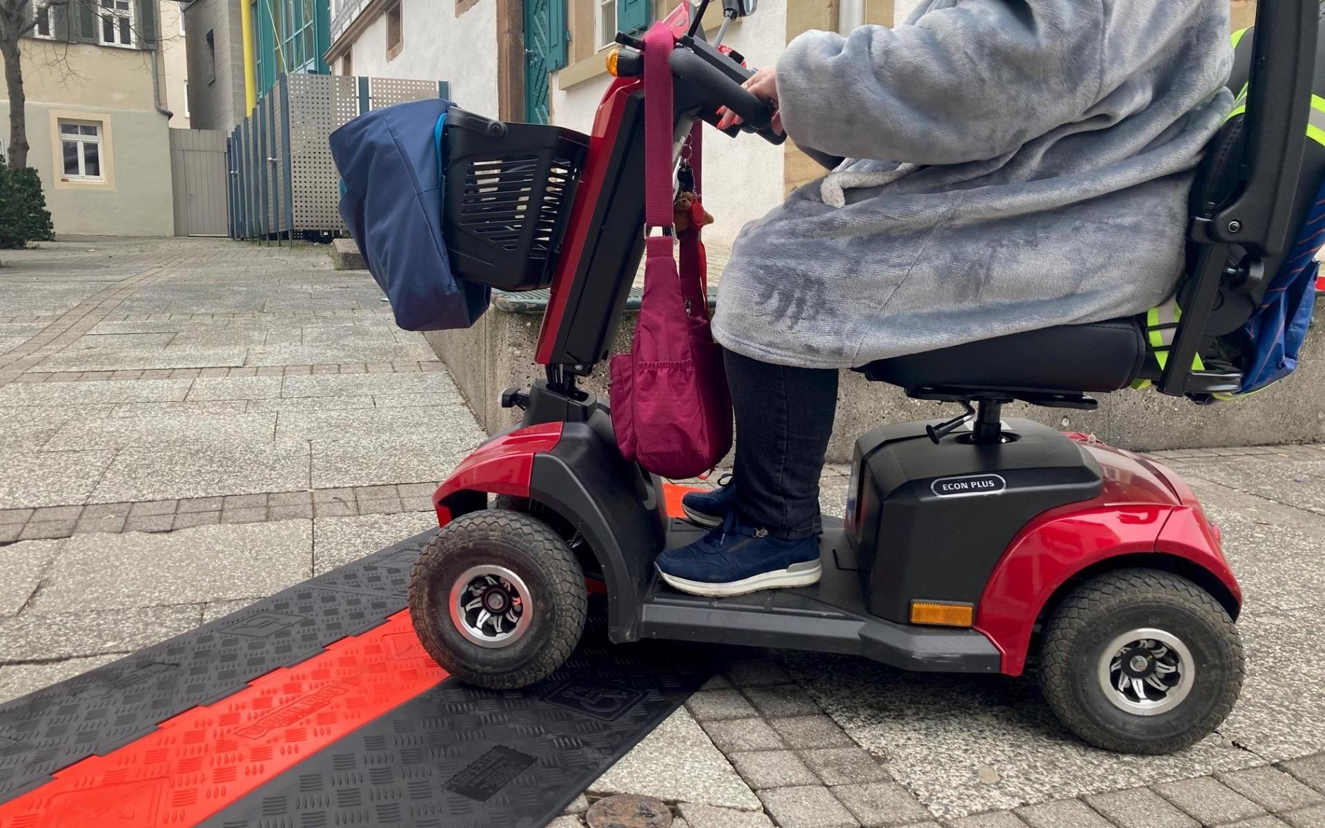 Eine Frau Befährt eine mit einem E-Scooter eine flache Kabelbrücke für Rollstühle