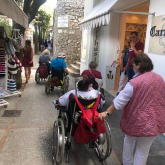 Eine Gruppe Rollstuhlfaher mit Begleitpersonen auf Einkaufstour