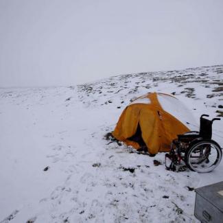 Im schnee auf einem Berg im Zelt wird übernachtet, der Rollstuhl steht daneben
