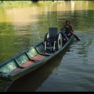 Auf einem Kanu in Borneo der Rollstuhl steht davor