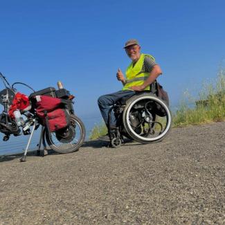 Bild zeigt Andreas Pröve im Rollstuhl mit abgekoppeltem Handbike bei einer Brotzeit am Marmarmeehr Bulgarien