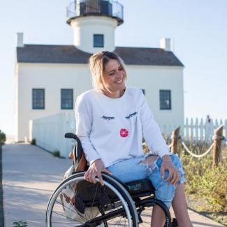 Roxana im Rollstuhl vor einem Leuchtturm 