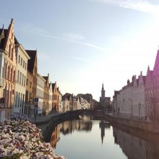Stadtansicht von Brügge: Häuser an beiden Ufern eines Kanals, sie spiegeln sich im Wasser.