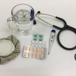 Bild zeigt Medikamente, Fieberthermometer, Stetoskop Wasserglas