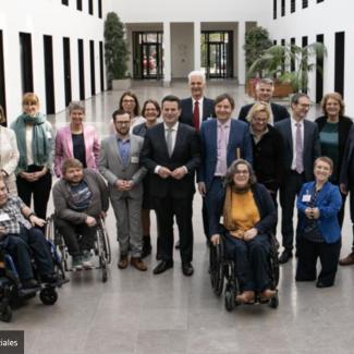 Bild zeigt eine Gruppe mit Menschen Stehend und im Rollstuhl in der Mitte Minister Hubertus Heil 