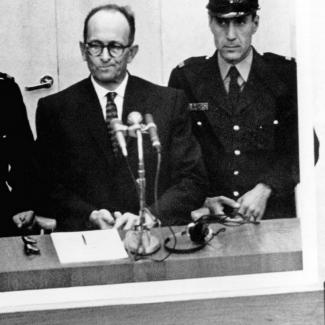 Bild zeigt Bild aus dem Gerichtsaal Eichmann mitte umringt von Justizbeamten in Uniform