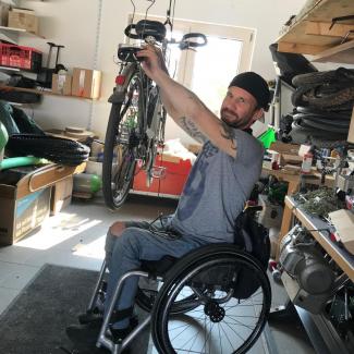 Rollstuhlfahrer Peter in seiner Werkstatt bei restaurieren von Fahrräder für Hochwasseropfer