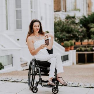 Bild zeigt Samanta Bullock im Rollstuhl auf das Hani blickend vor einer Häuserreihe in England
